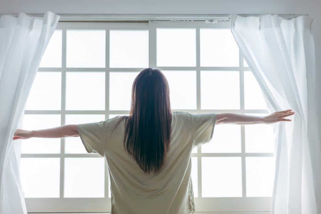 カーテンを開ける女性の画像